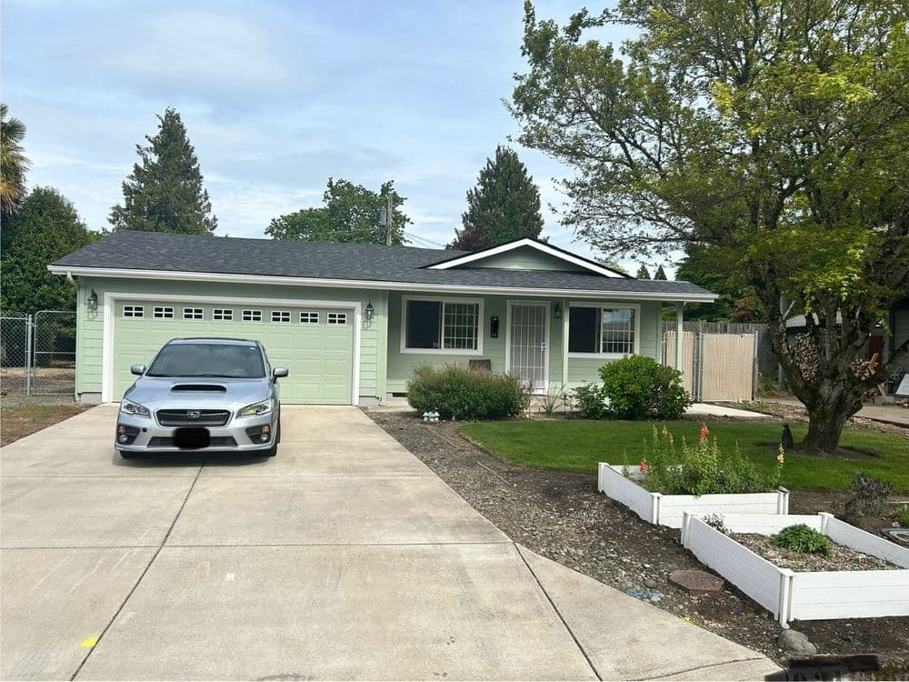 Modern single-story home with garage and landscaped front yard. Gray car in driveway.
