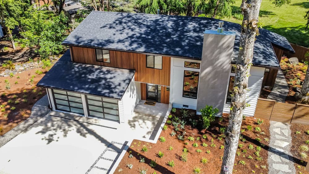 Modern two-story house with wooden accents, large windows, and landscaped outdoor space.