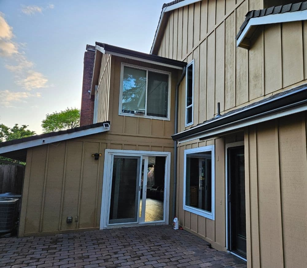 Exterior view of a modern home with patio and large windows in evening light.