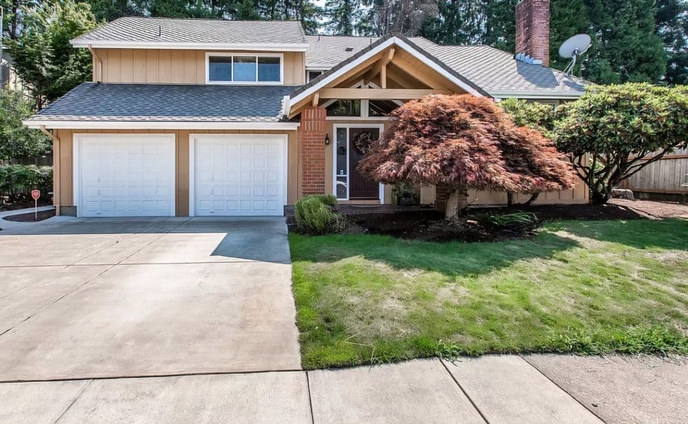 Two-story suburban home with garage, manicured lawn, and colorful landscaping.