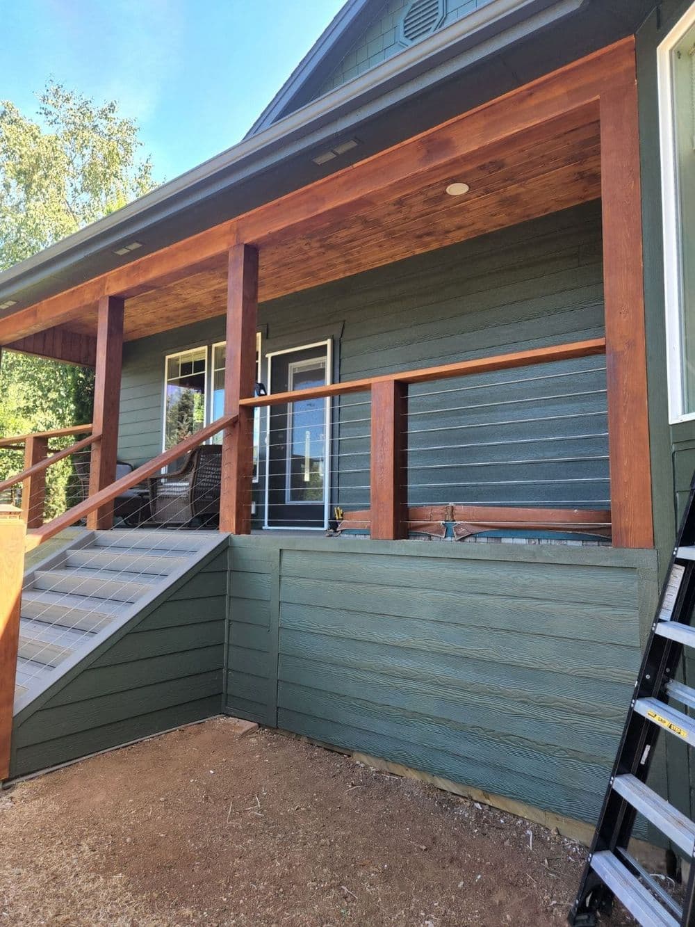 Newly constructed home with a blue exterior, wooden porch, and accessible entry stairs.
