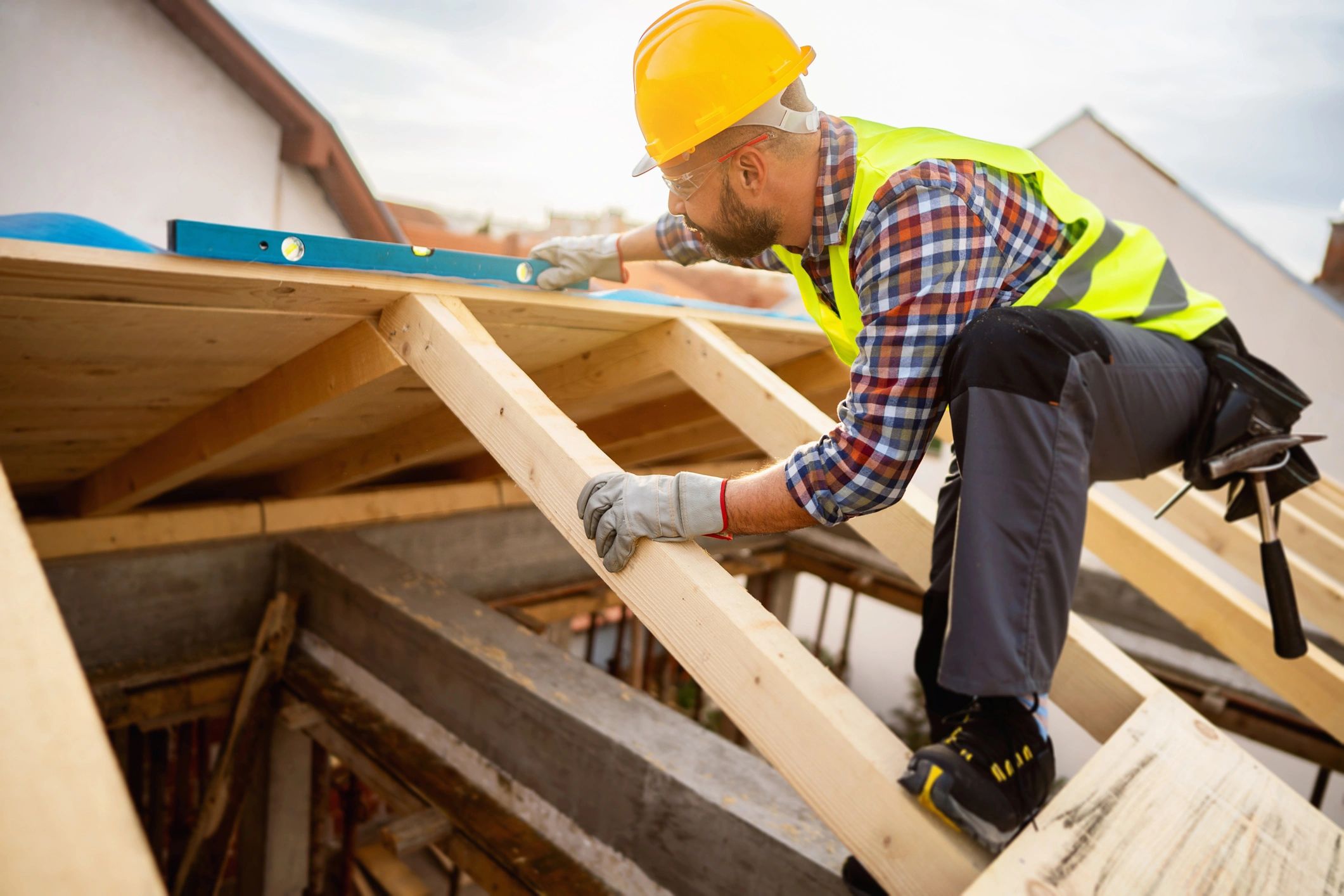 Roofer using a level while checking roof structure